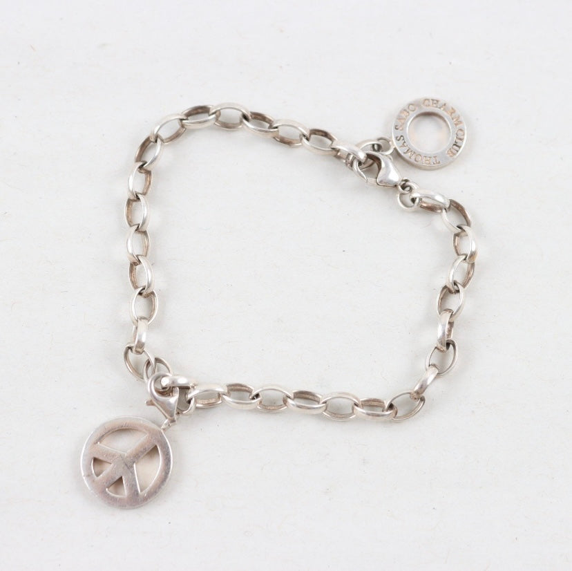 Silver bracelet with peace sign charm on a white background
