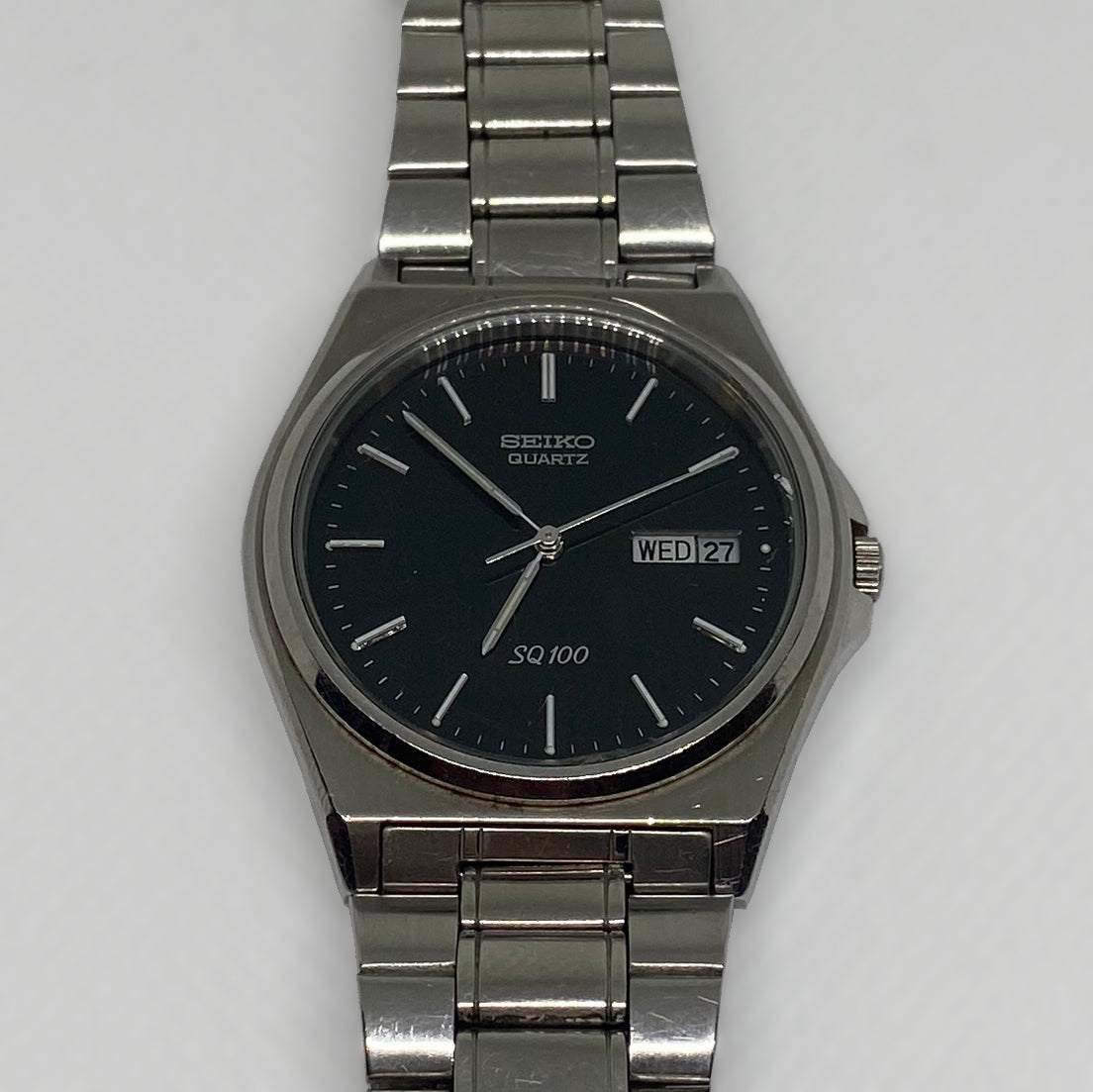 Silver Seiko watch with black dial on a light gray background