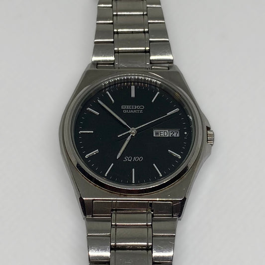 Silver Seiko watch with black dial on a light gray background