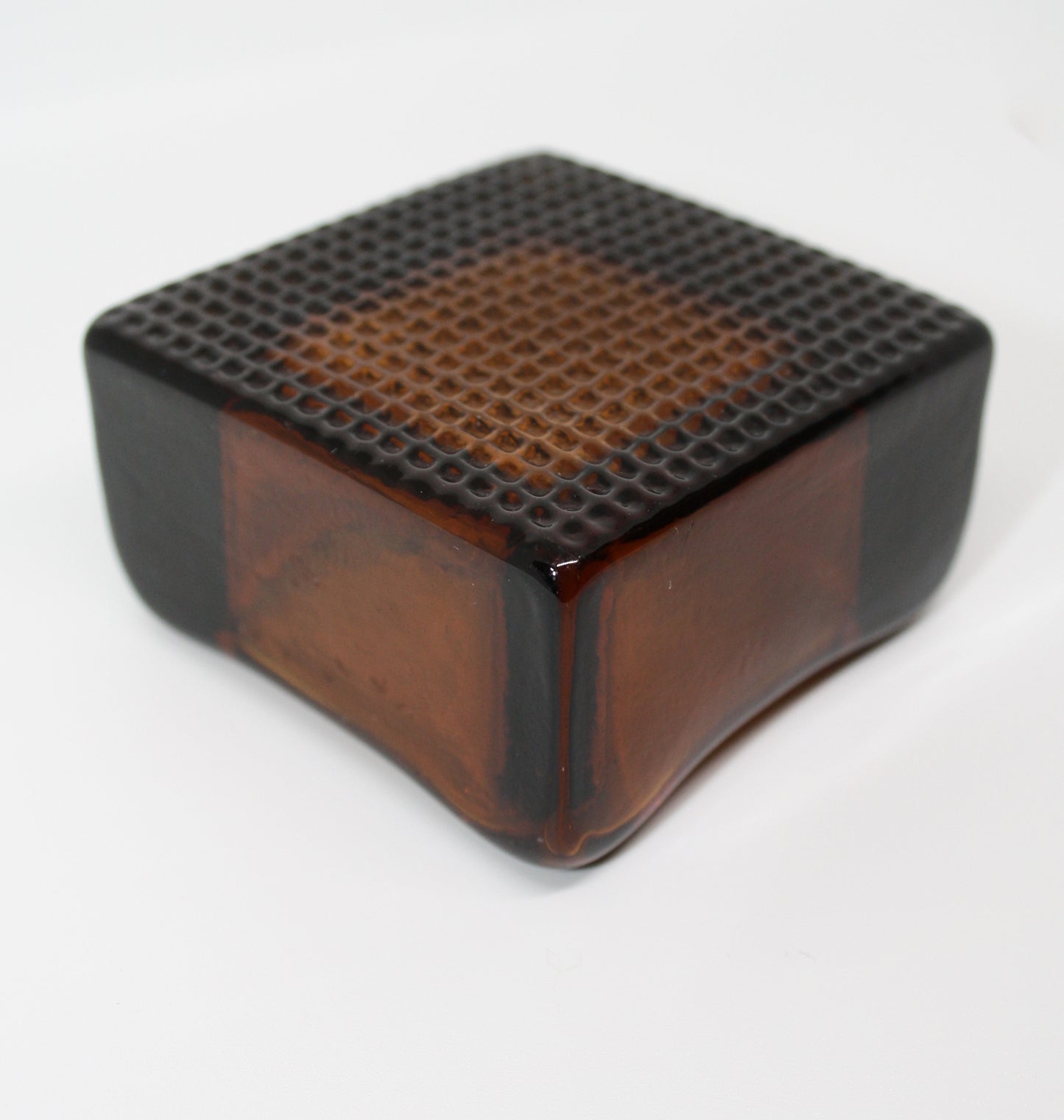 Amber glass cube with textured surface on a white background