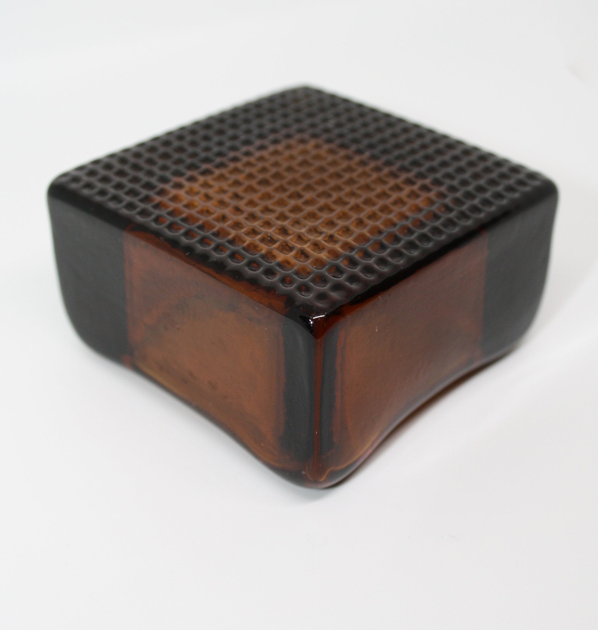 Amber glass cube with textured surface on a white background
