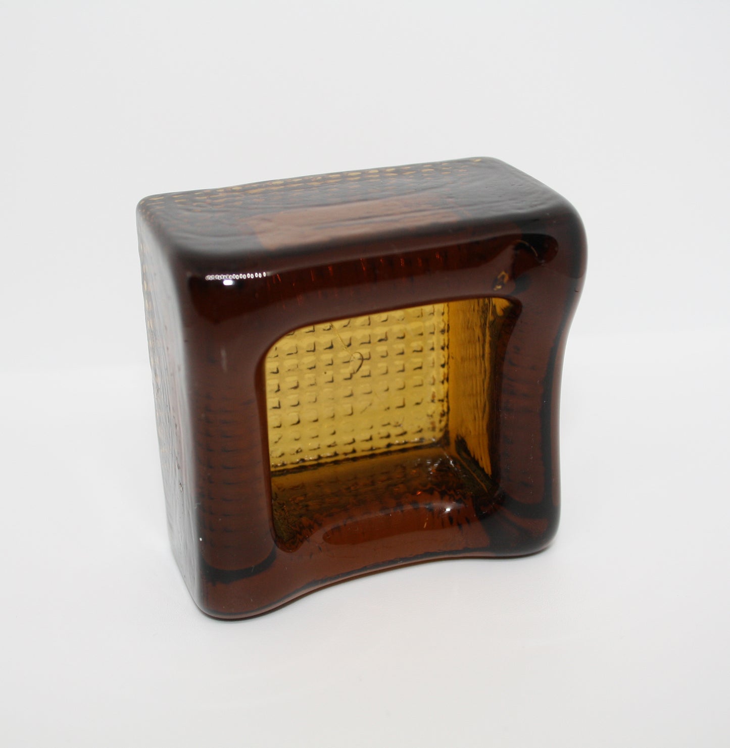 Amber glass block with textured interior on a white background