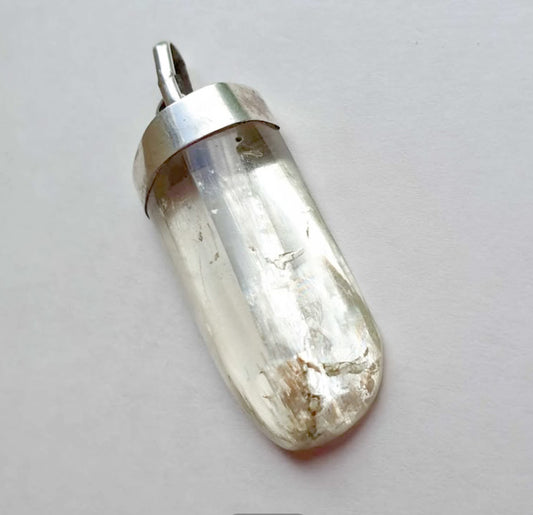 Clear rock crystal with silver bail on a light gray background