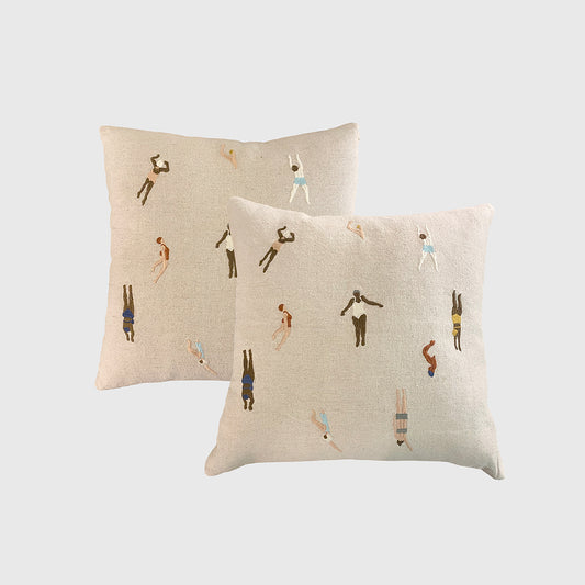 Two beige pillows with embroidered designs on a white background