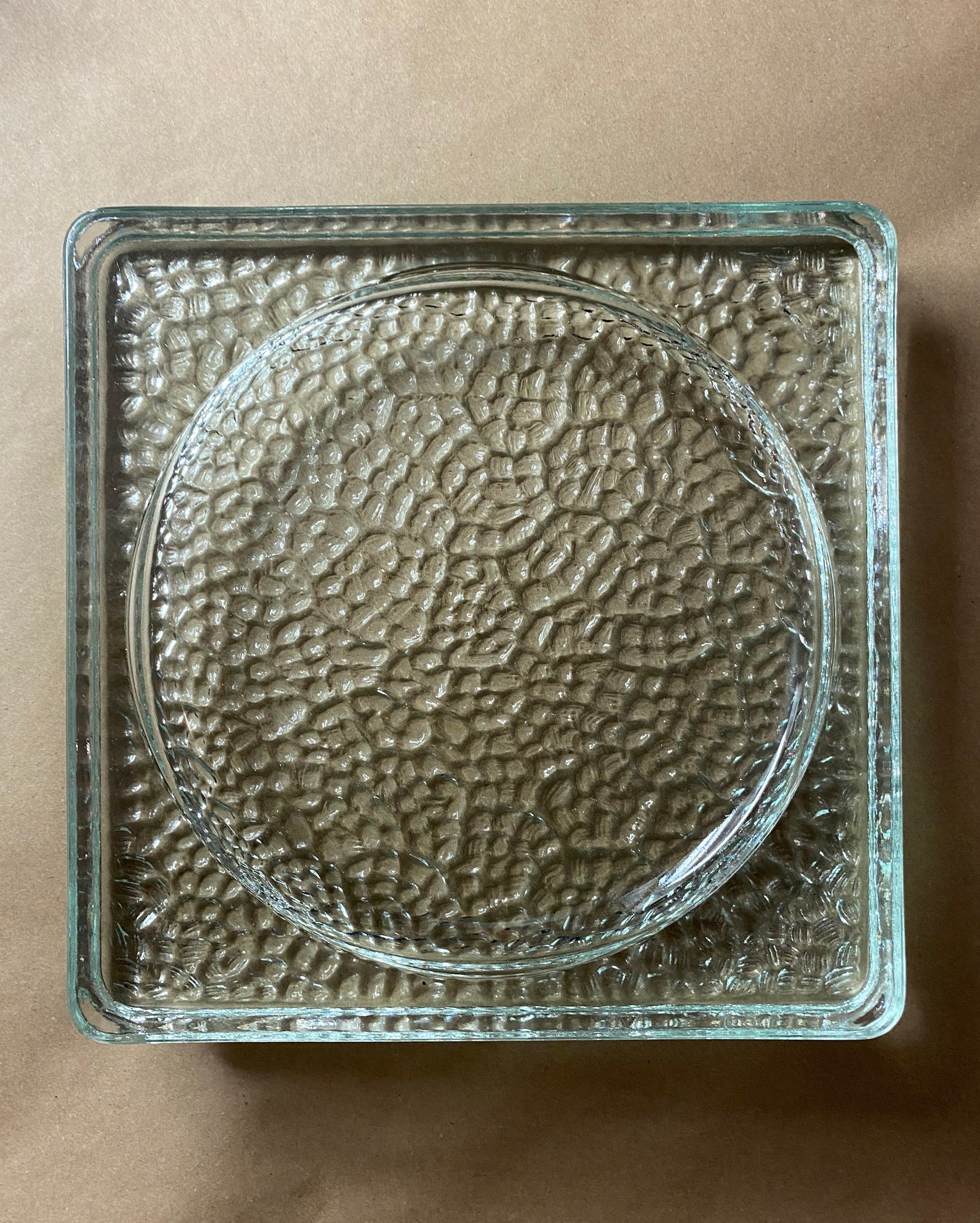 Clear glass block with textured surface on a brown background