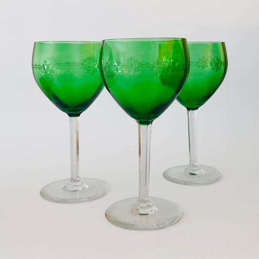 Three green wine glasses on a white background